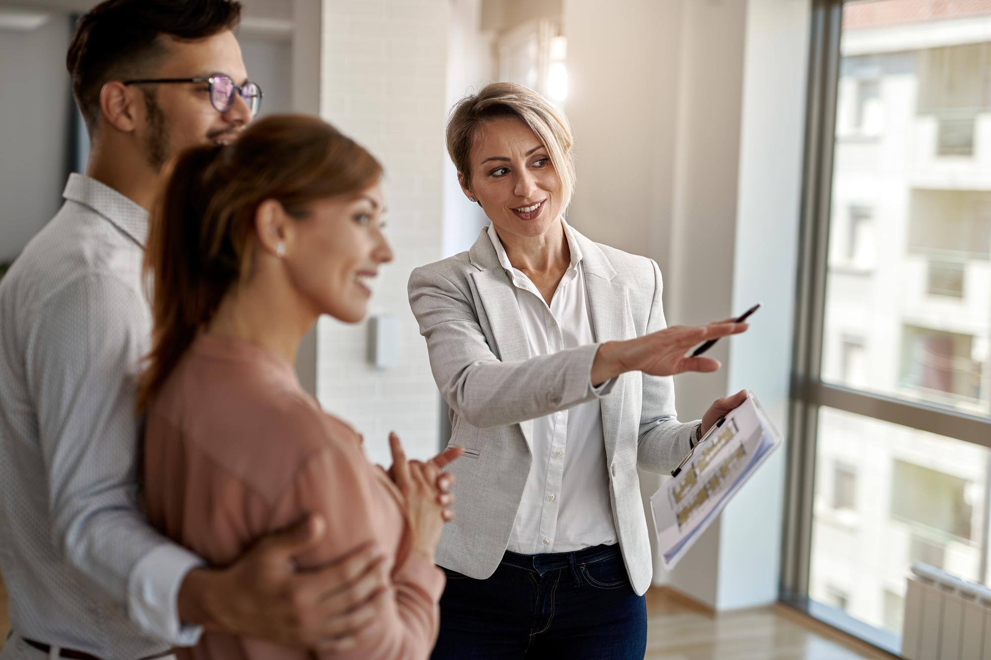 smiling-real-estate-agent-talking-with-couple-interested-buying-new-home